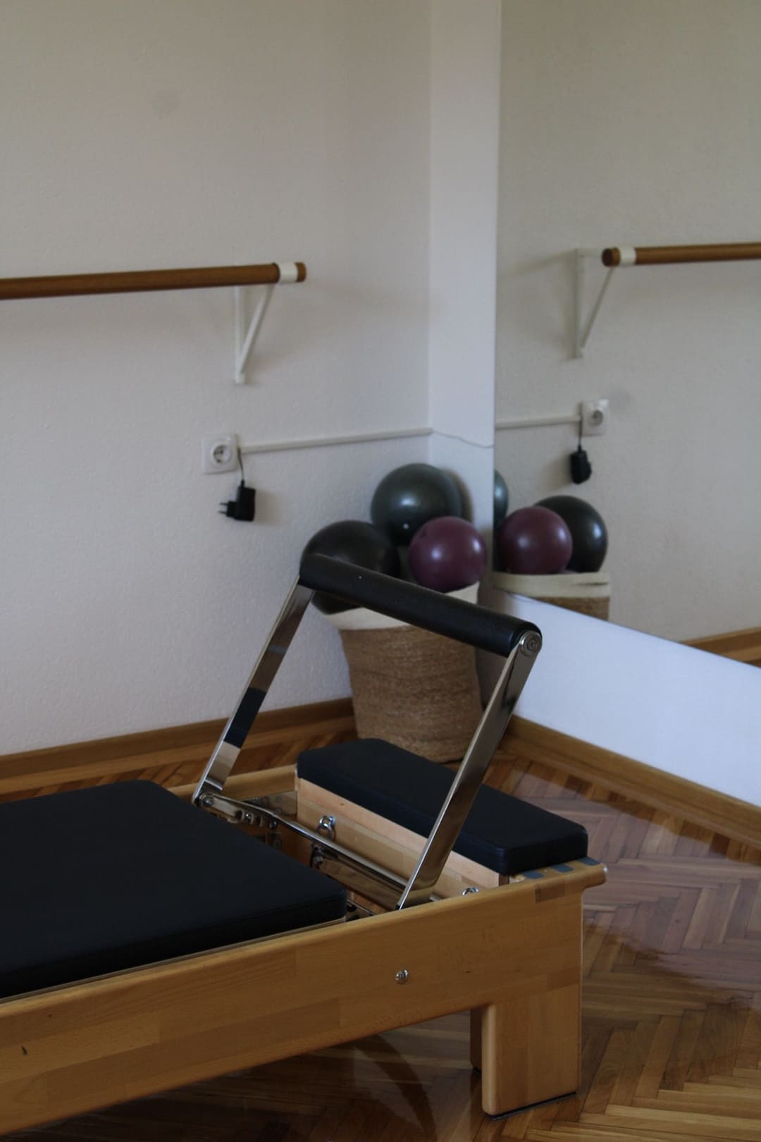 Reformer od svetlog drveta i korpa sa loptama za pilates