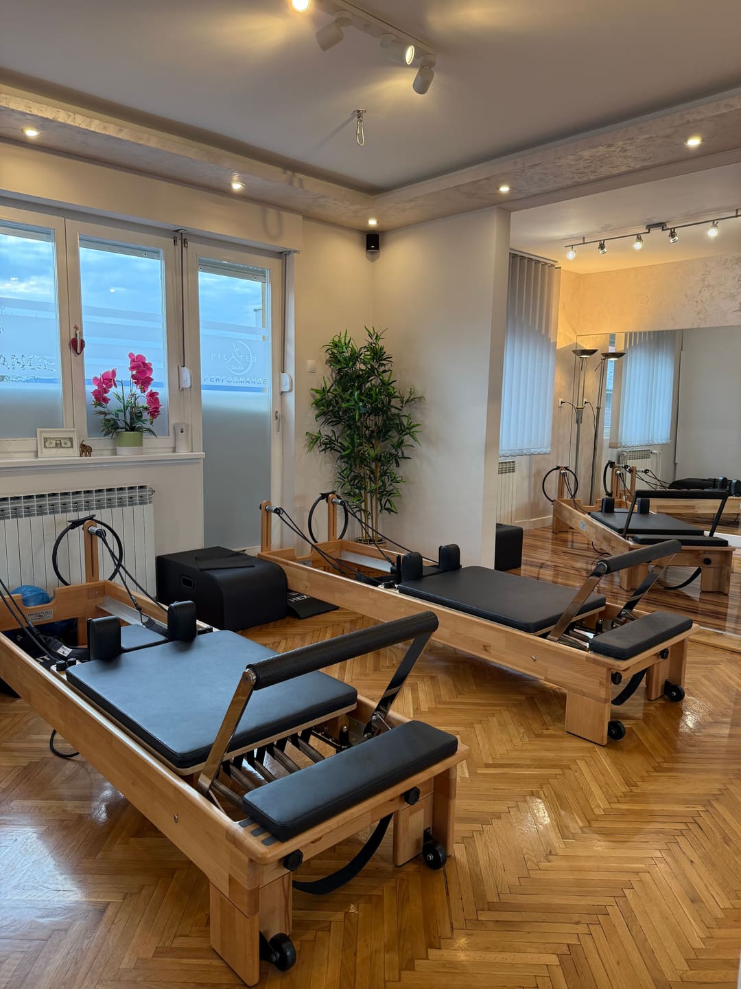 Studio Pilates Studio Performance: reformeri, prozor sa logom i orhideja